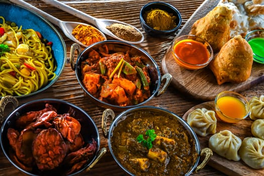 Composition with indian dishes: samosa, pakora, palak paneer, jalfrezi, thukpa and naan bread