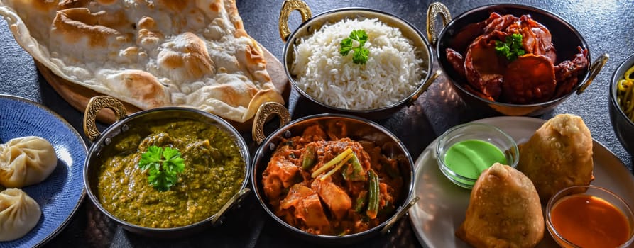 Composition with indian dishes: samosa, pakora, palak paneer, jalfrezi, thukpa and naan bread