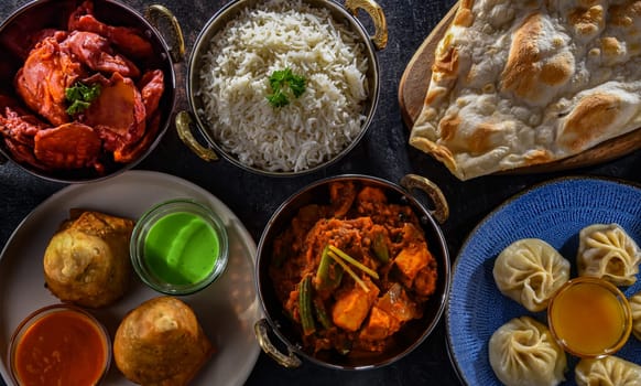 Composition with indian dishes: samosa, pakora, palak paneer, jalfrezi, thukpa and naan bread