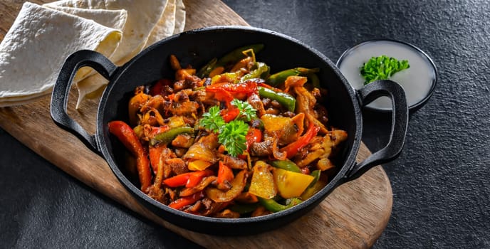Fajita with stripped peppers and onions served on a hot iron skillet