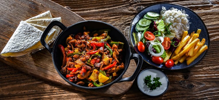 Fajita with stripped peppers and onions served on a hot iron skillet