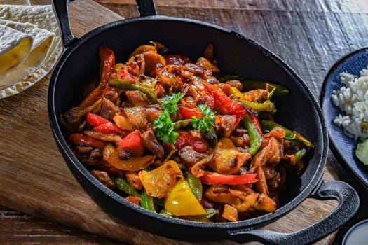 Fajita with stripped peppers and onions served on a hot iron skillet