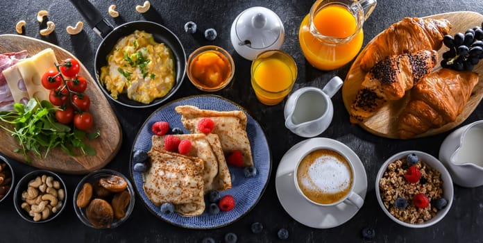 Breakfast served with coffee, orange juice, scrambled eggs, cereals, pancakes and croissants.