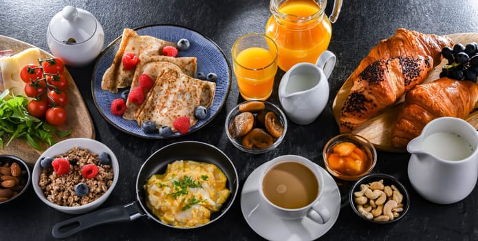 Breakfast served with coffee, orange juice, scrambled eggs, cereals, pancakes and croissants.