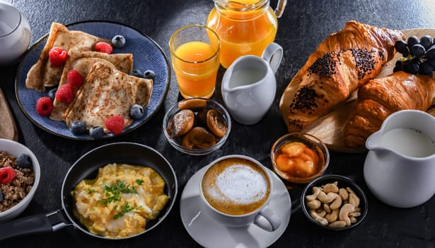 Breakfast served with coffee, orange juice, scrambled eggs, cereals, pancakes and croissants.