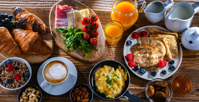 Breakfast served with coffee, orange juice, scrambled eggs, cereals, pancakes and croissants.