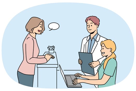 Woman client of clinic stands near reception desk and consults with doctor or chooses convenient time for next appointment. Employees of cosmetology clinic and potential patient are in lobby