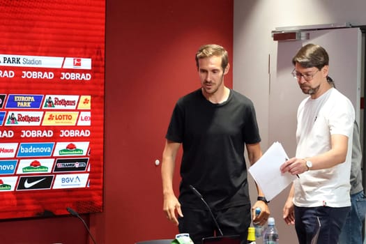 Together with press officer Sascha Glunk (left),head coach Julian Schuster (SC Freiburg) enters the press room for the first time after the start of training for Bundesliga club SC Freiburg 2024  DFL REGULATIONS PROHIBIT ANY USE OF PHOTOGRAPHS AS IMAGE SEQUENCES AND/OR QUASI-VIDEONann  Photo: Joachim Hahne/johapress