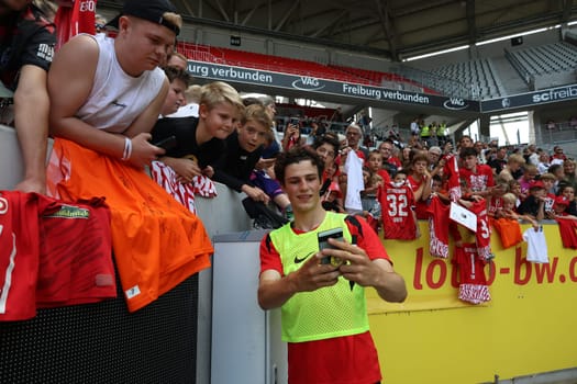 Merlin Röhl (SC Freiburg) takes a quick selfie with the young fans after the start of training Bundesliga club SC Freiburg 2024  DFL REGULATIONS PROHIBIT ANY USE OF PHOTOGRAPHS AS IMAGE SEQUENCES AND/OR QUASI-VIDEONann  Photo: Joachim Hahne/johapress