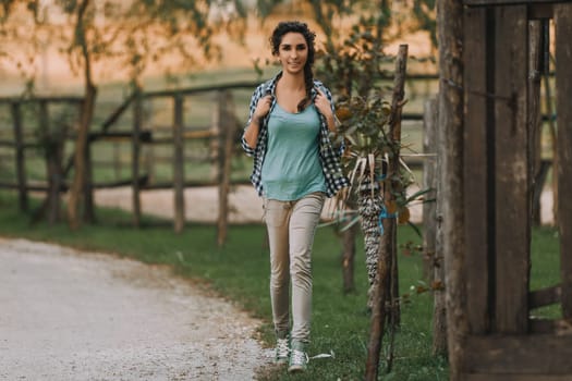 Woman with braided curly hair, wearing a checkered shirt and green top, walks outdoors smiling. Her joyful expression and relaxed posture indicate a peaceful, happy atmosphere