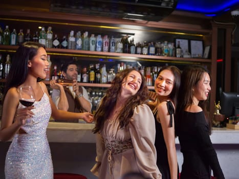Happy People Group clink wine glasses for cheers in night club at counter. Celebration, friends and party concept.