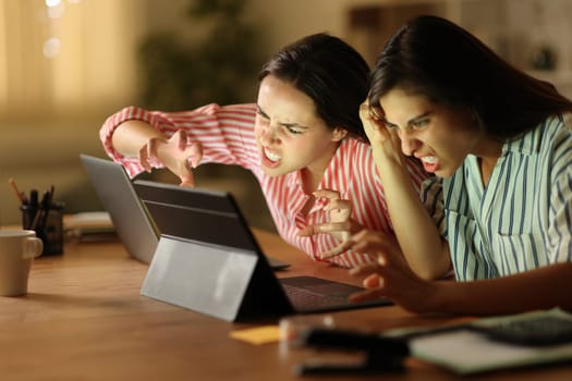 Angry tele workers checking laptop in the night at home