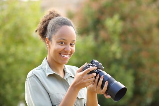 Happy black photographer looks at camera in a park