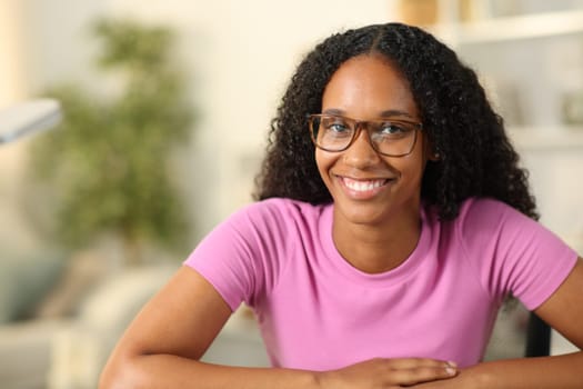 Happy black woman with eyeglasses looks at you at home