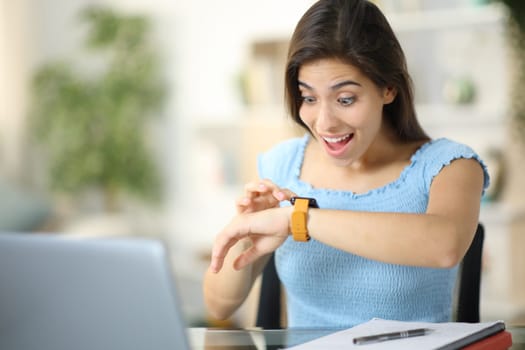 Surprised student checking smartwatch content at home