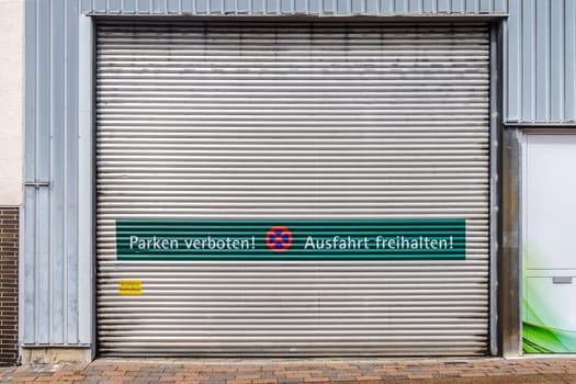 Rolling gate with the words parking prohibited and keep the exit clear in German