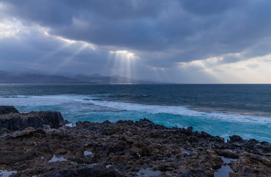 Beautiful sunrays on the Atlantic coast in Las Palmas de Gran Canaria, view from Las Canteras beach