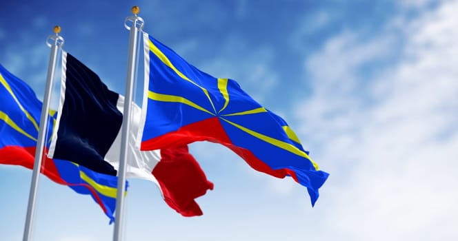 Reunion and national french flags waving on a clear day. Island in the Indian Ocean and overseas department and region of France. 3d illustration render. Selective focus