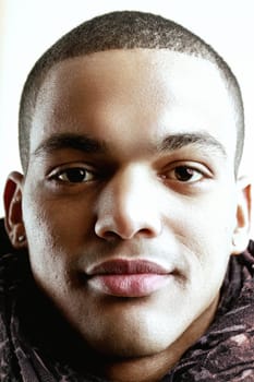 Close-up of a young man with dark skin, short hair, and earrings. His expression is neutral, with slightly parted lips and relaxed eyes, conveying a calm and composed demeanor