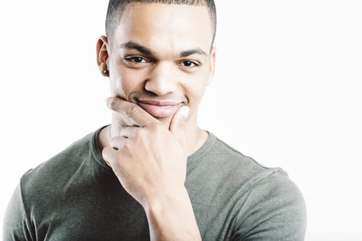 Young man in a green shirt, smiling thoughtfully with his hand on his chin. His expression and casual attire convey a sense of contemplation and confidence, suggesting he is pondering something intere
