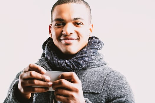 Man in a grey coat and scarf, holding a smartphone with a smile. His friendly expression indicates he is enjoying a pleasant interaction or communication on his phone