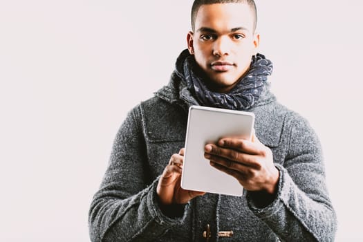 Individual in a grey wool coat and blue scarf, attentively engaging with a digital tablet. His focused expression reflects a preference for informed knowledge over uninformed belief