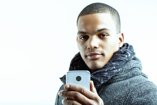 Individual with no smile, holding a smartphone in both hands. Wearing a grey coat and scarf, he appears to be enjoying a moment of interaction on his device