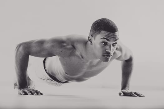 Black man in a 1950s style, performing a push-up with intense focus. His muscular build and serious expression reflect his dedication as a boxer training for strength and endurance