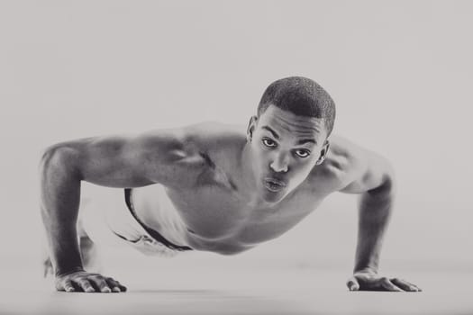 Muscular black man in vintage 1950s style doing push-ups, showcasing his physical strength and determination. His intense gaze and defined muscles emphasize his commitment to boxing