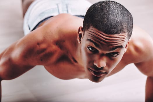 Man with a concentrated look, doing push-ups and displaying a toned body. His short hair and intense focus underline his commitment to maintaining physical fitness and health