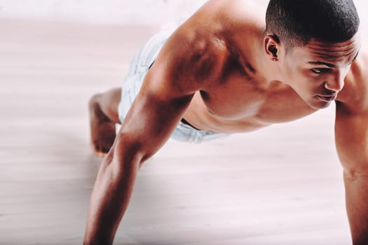 Focused individual doing push-ups, with a muscular build and short hair. His determined expression highlights his commitment to rigorous physical exercise and maintaining fitness