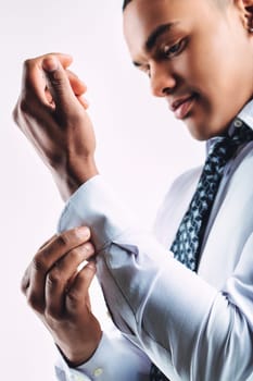 Young man adjusting his shirt cuff, dressed in a white shirt and patterned tie. His focused expression and attention to detail suggest a professional attitude and readiness for a formal setting