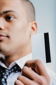 Man in a white shirt with a patterned tie, extending a business card. His confident demeanor and formal attire indicate he is prepared for professional engagements and networking