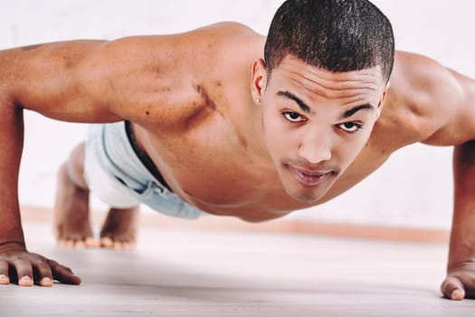Young man performing push-ups, showcasing a strong and fit physique. His focused expression and short hair highlight his dedication to physical fitness and exercise, emphasizing determination