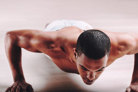 Man with an intense gaze, performing push-ups and exhibiting a toned physique. His short hair and serious expression underscore his dedication to physical fitness and discipline