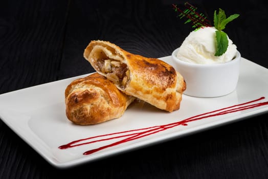 Apple strudel with vanilla ice cream decorated with caramel and berries sauce