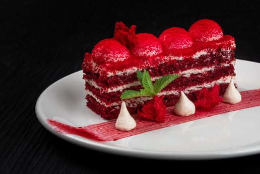 Plate with piece of delicious red velvet cake on black wooden background, food and drink concept