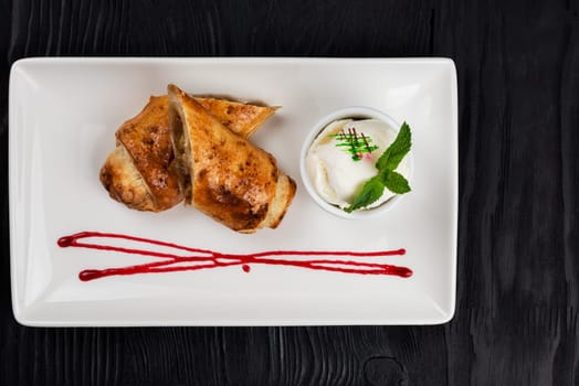 Apple strudel with vanilla ice cream decorated with caramel and berries sauce