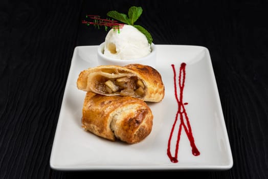 Apple strudel with vanilla ice cream decorated with caramel and berries sauce