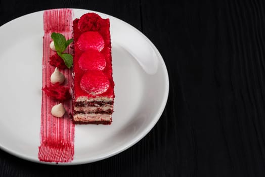 Plate with piece of delicious red velvet cake on black wooden background, food and drink concept