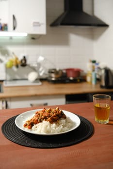 Homemade spicy chicken stew with vegetables and rice on a kitchen table