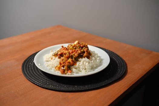 Plate with chicken ragout with vegetables and rice on kitchen table