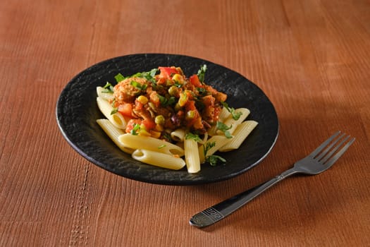 Beef slices fried with vegetables and spicy sauce with pasta on wooden background
