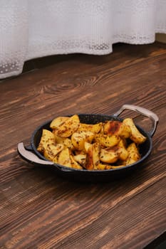 Baked potato wedges with spices, herbs and garlic in baking pan
