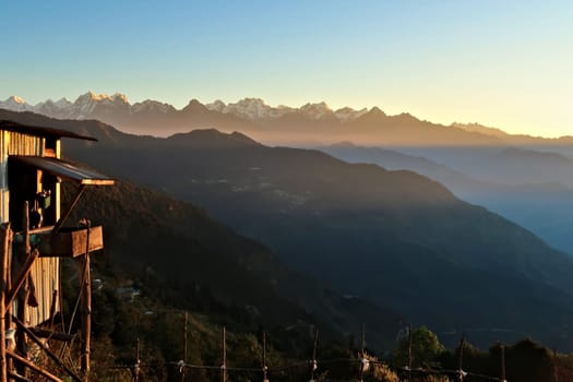 Wooden farmers house in front of the Himalaya Mountain Range in the distance at golden hour, seen on the off-road ride from kathmandu to Salleri, Phaplu, Bupsa, Jubing, Nepal 2022