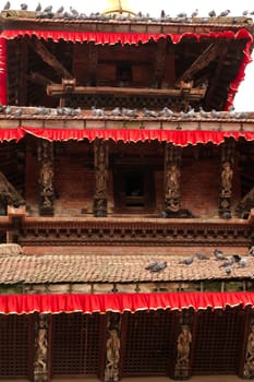 Closer look on the architecture of one of the temples of Durbar Square, many pigeons are sitting on its roofs, Kathmandu, Nepal 2022