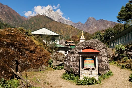 Colorful prayer wheel in front of big Mani stone in the Chhuthawa, Ghat village, Chaurikharka on the Everest Basecamp Trek, Nepal 2022