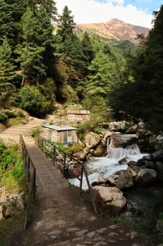 View onto the Manjo Bridge, stone houses are standing right next to the river with little waterfalls, Manjo, Monjo Village, Mount Everest Basecamp Trek, EBC, Nepal 2022