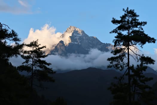 The peak of Mount Khumbila at sunset, view between the trees from the monastery of Monjo, Manjo village, Mount Everest Basecamp Trek, EBC, Nepal 2022