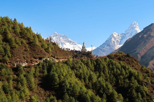 View onto the Tenzing Norgay Memorial Chhorten, Stupa near Namche Bazaar, Bazar, Lhotse and Ama Dablam can be seen in the background, many people are gathering in the foreground, Mount Everest Basecamp Trek, EBC, Nepal 2022